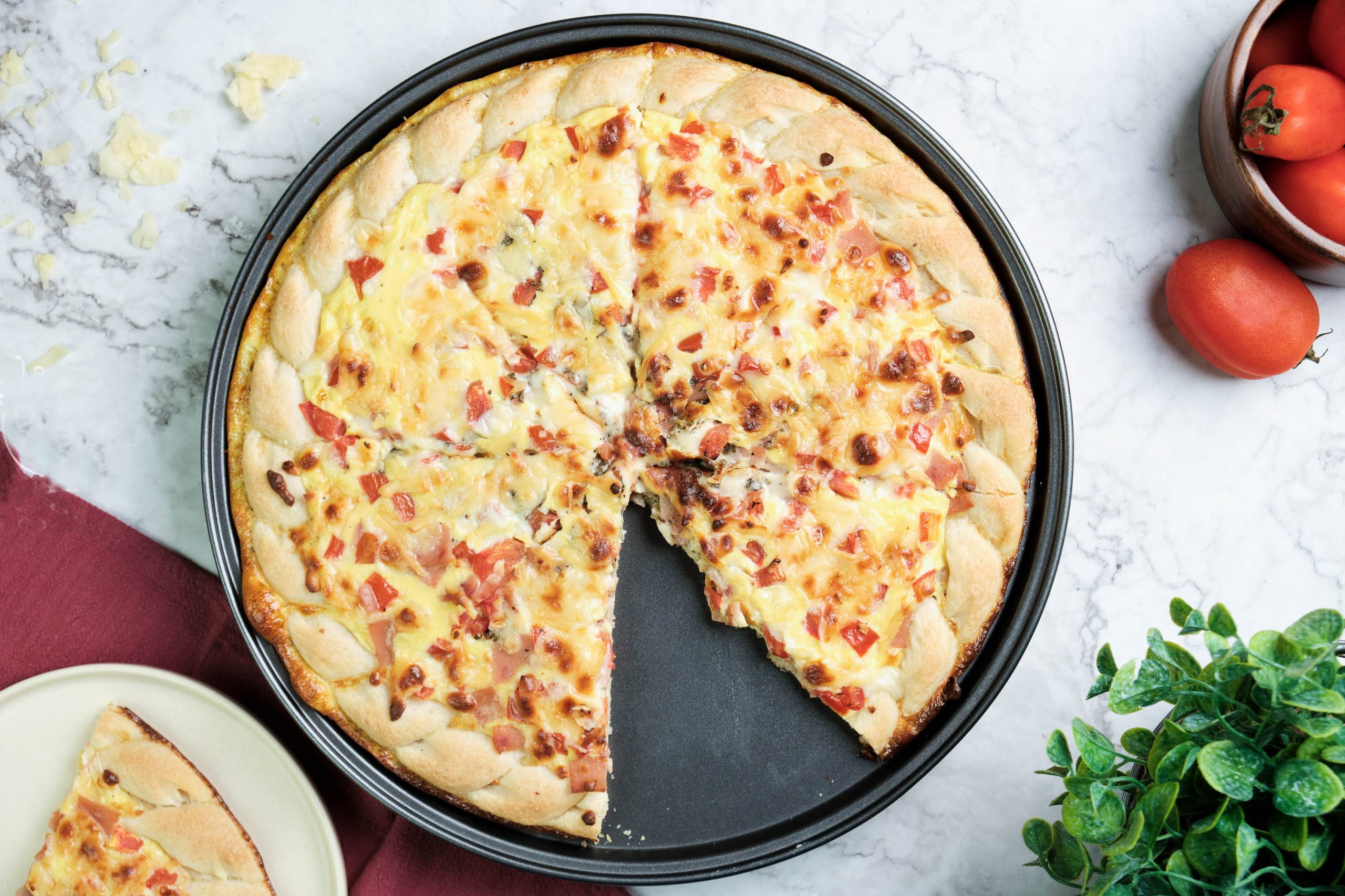 A Cheddar and Ham Breakfast Pizza in a pan with a slice missing.