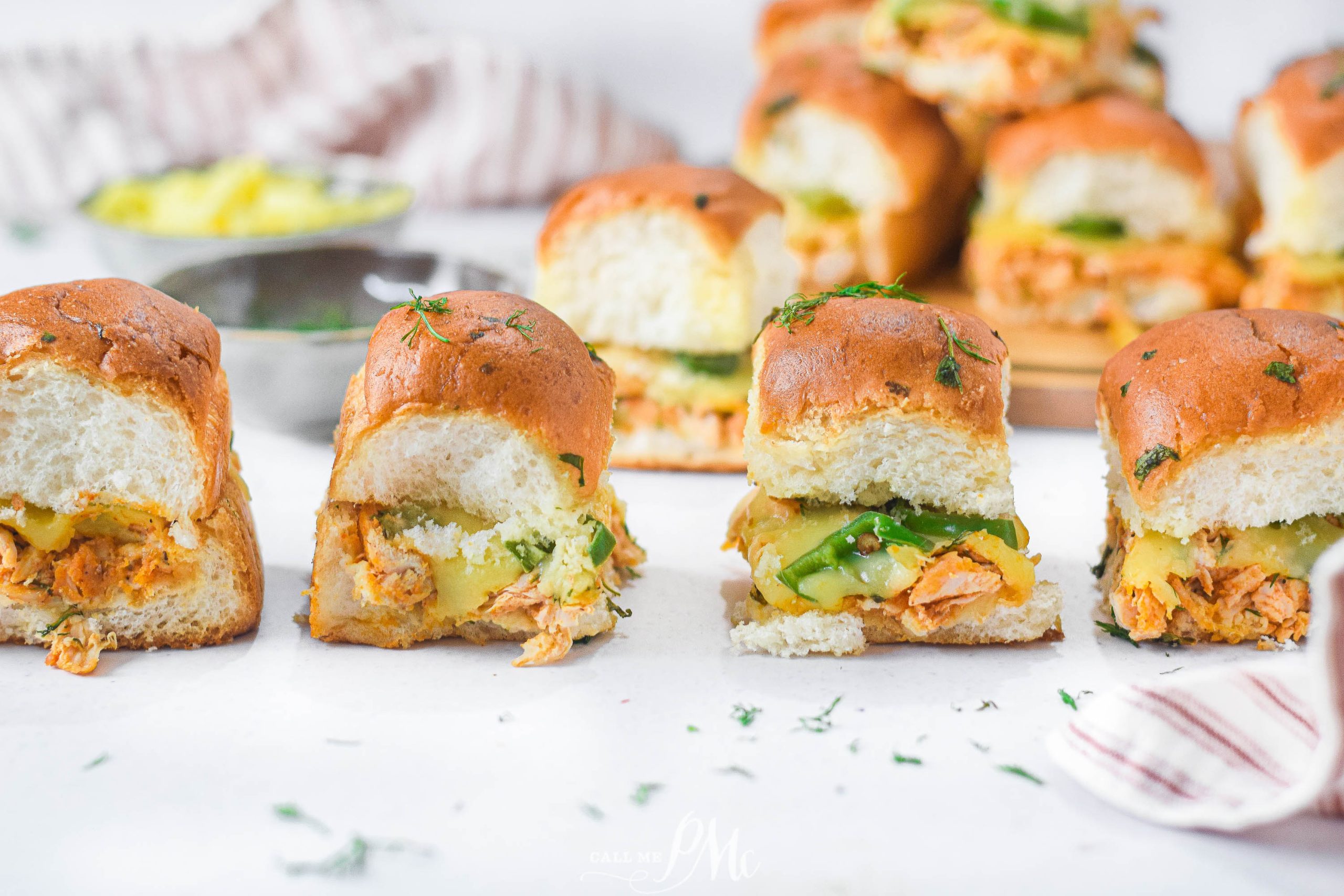 Small chicken sandwiches with cheese on a table.