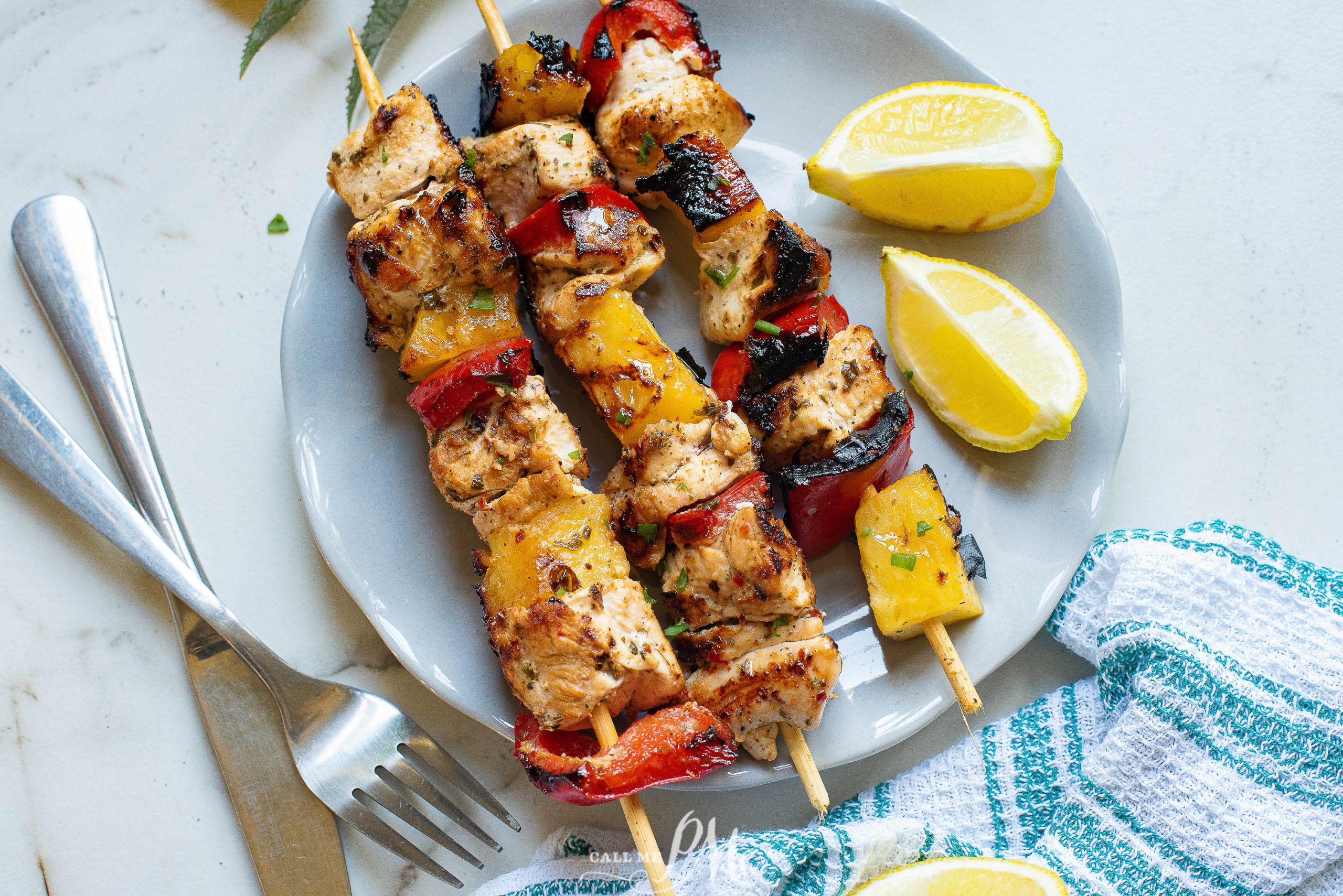 Pineapple chunks, peppers, and Chicken on Kabobs on a blue plate.