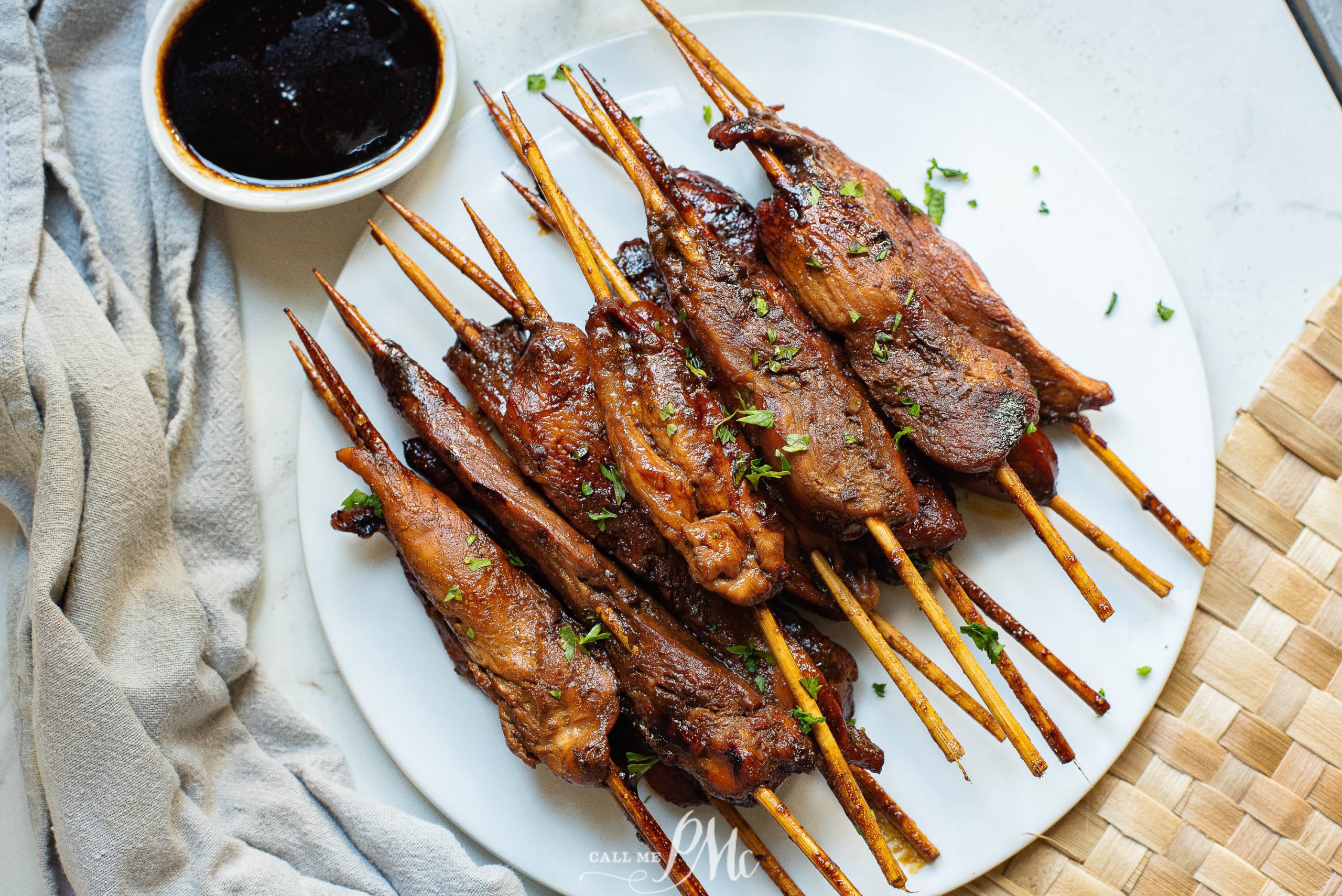 Cooked Chicken tenderloins on skewers on a white plate.