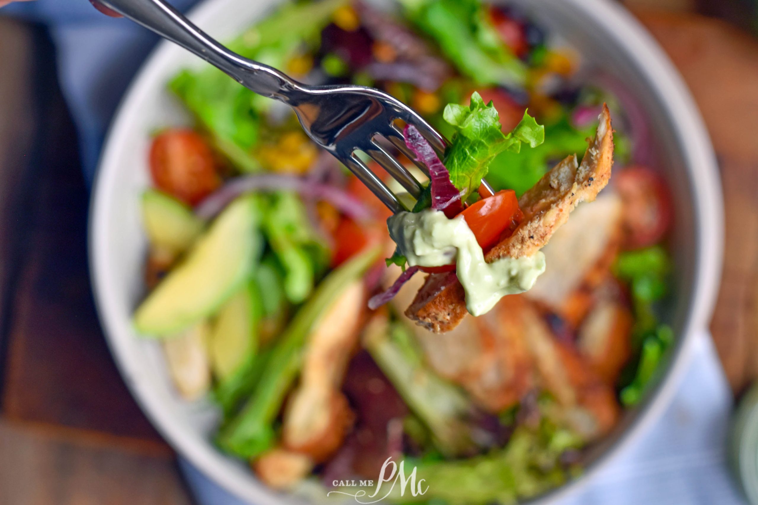  Blackened Chicken Salad bite on a fork with avocado sauce, lettuce, and tomato.