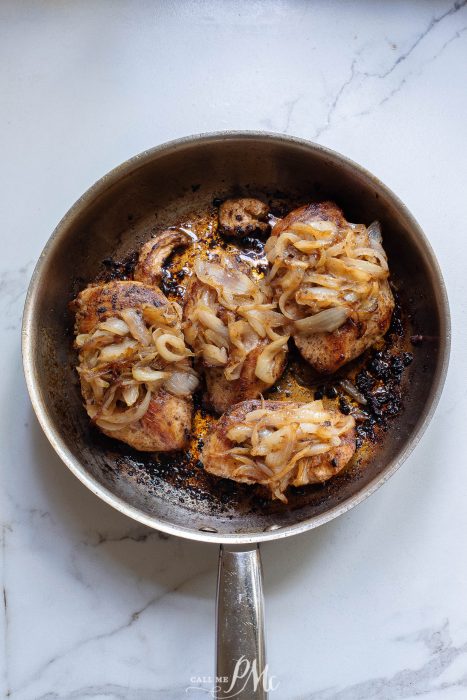 chicken topped with onions in pan