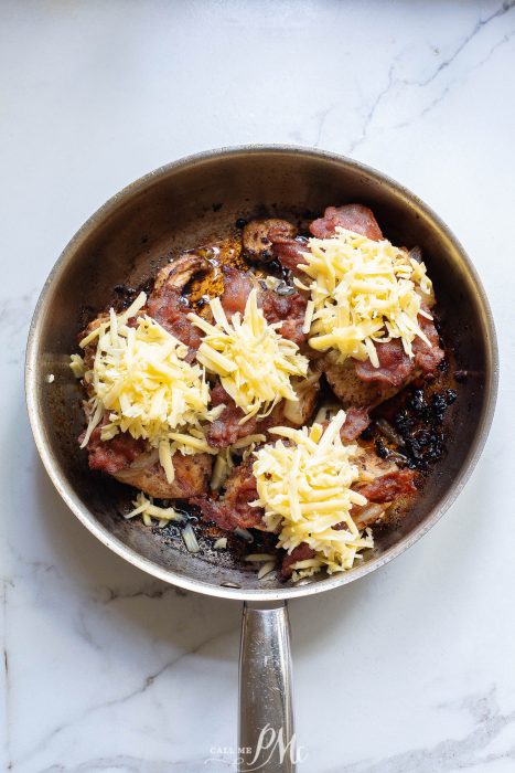 chicken topped with onions, bacon, and unmelted cheese in pan
