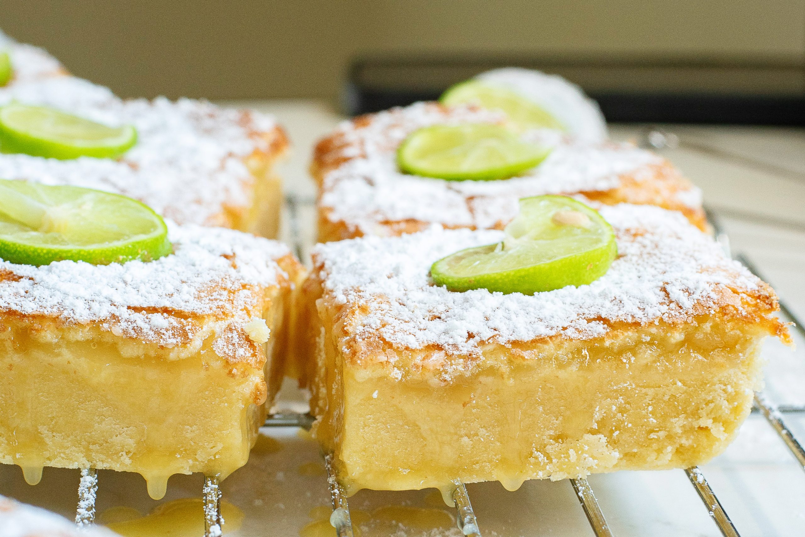 Margarita squares dessert on a wire rack with sauce dripping down.