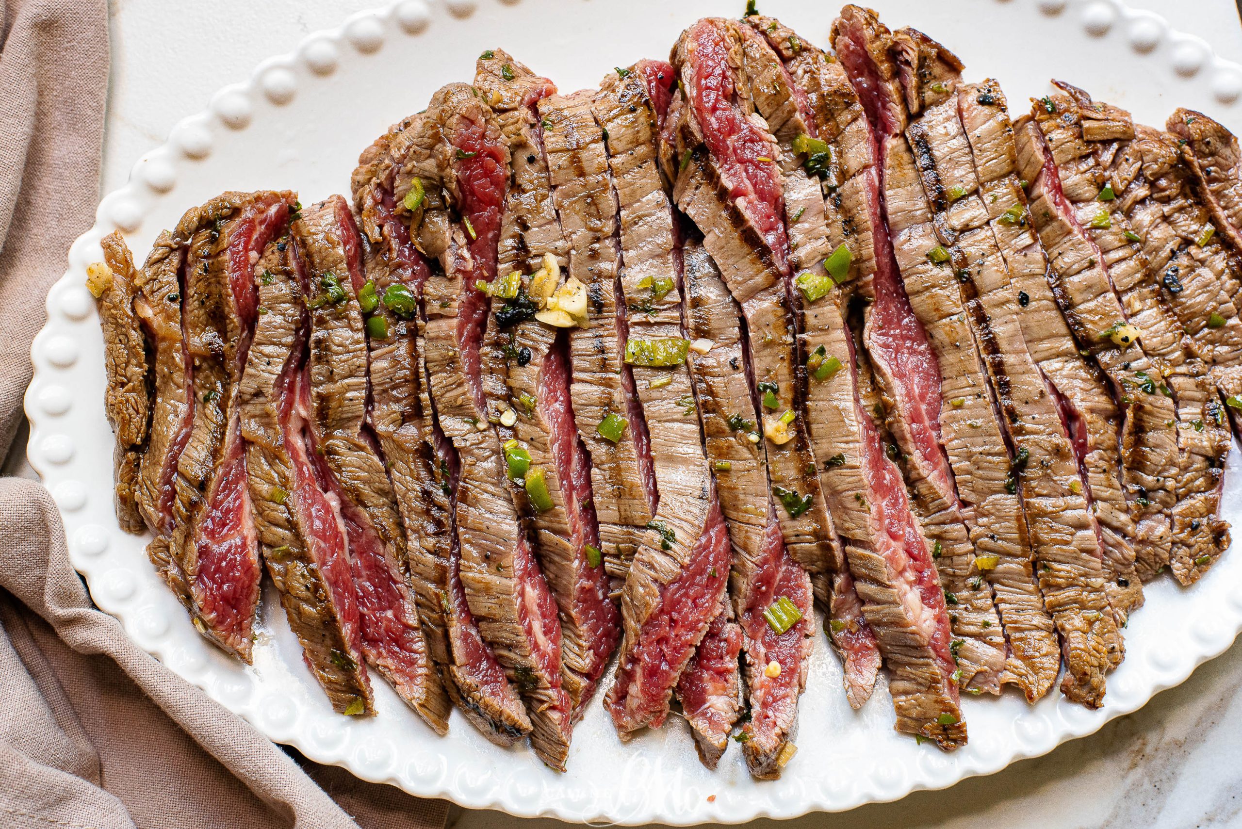 Marinated grilled meat, sliced and on a platter.