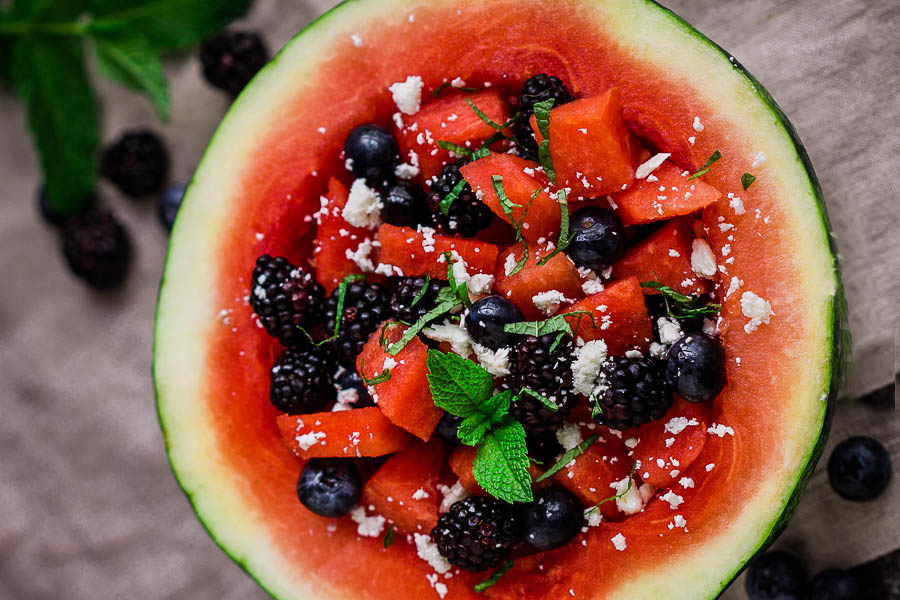half a watermelon with berries in it