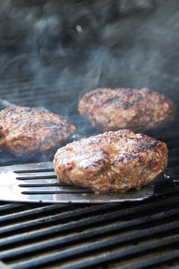 Hamburgers are being cooked on a grill.