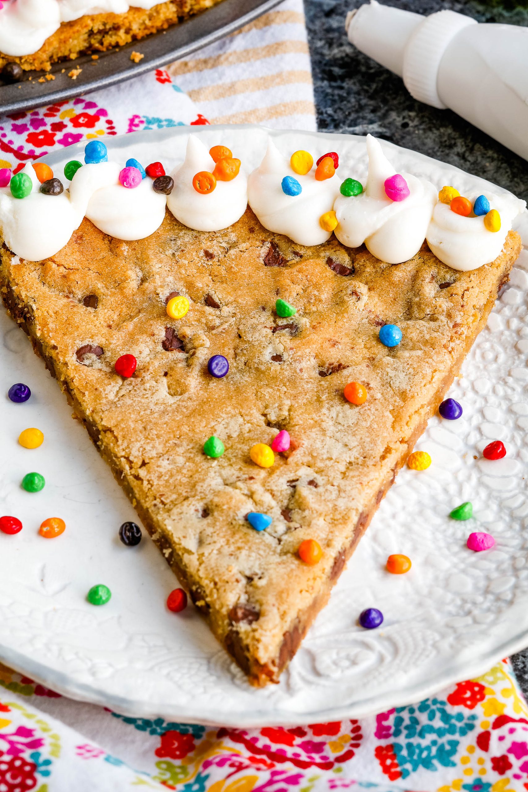 A slice out of a giant chocolate chip cookie on a plate.