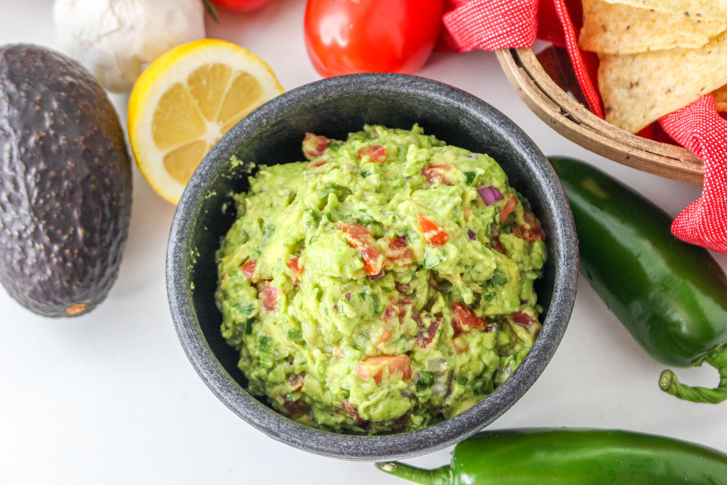 Mexican dip in a dark bowl with avocados and jalapenos.