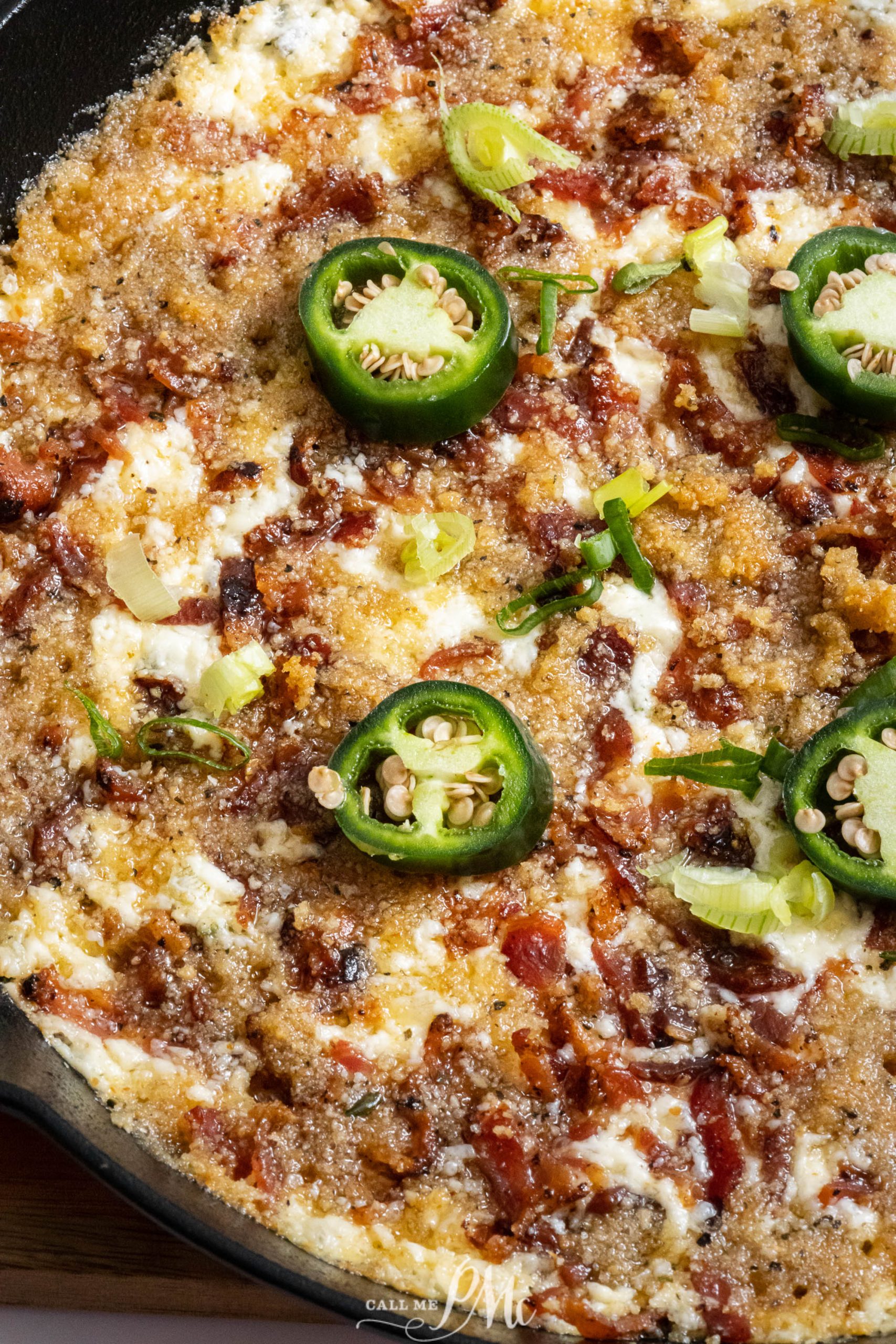 A bowl full of dip with bacon and jalapenos.