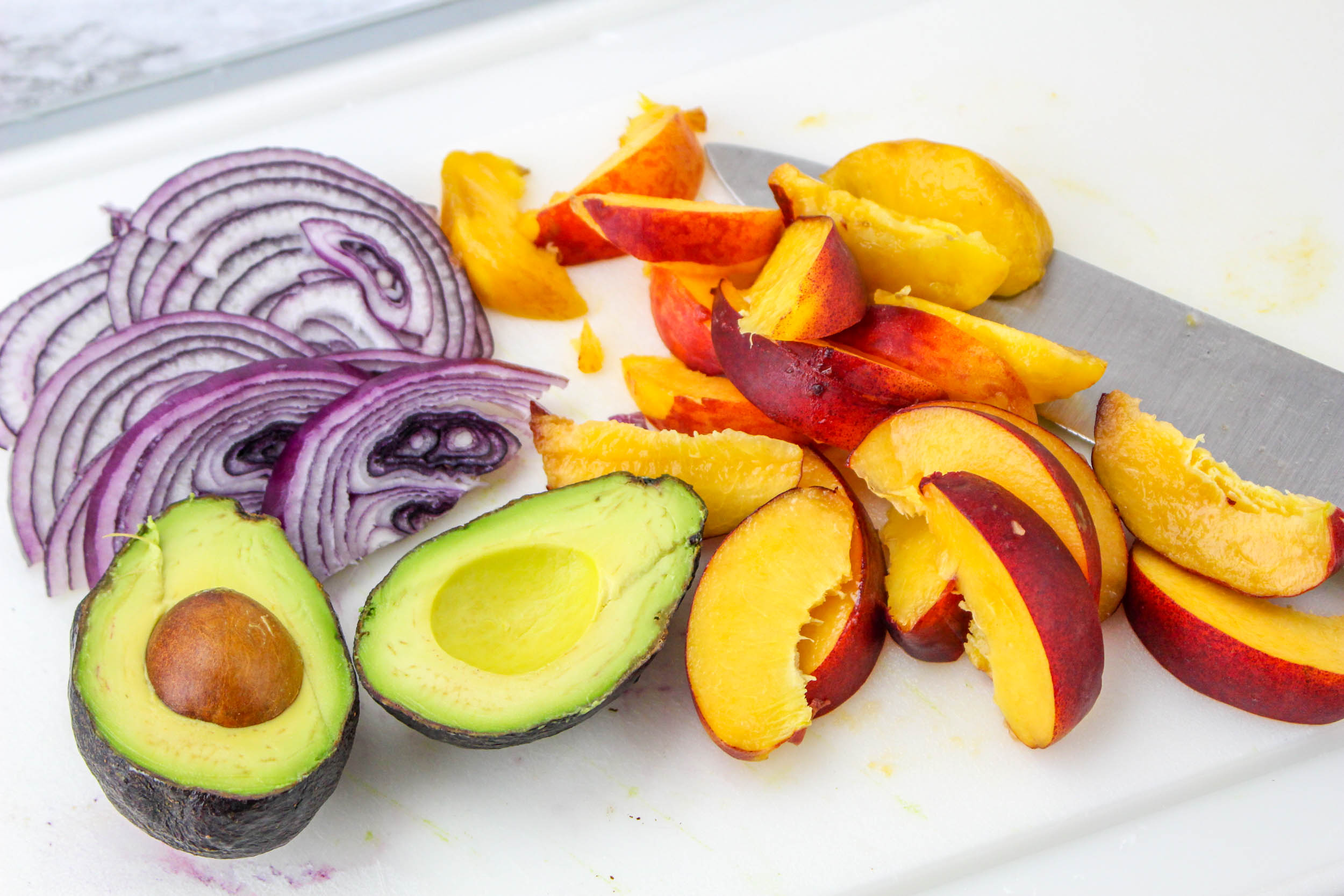 Peaches, avocado, and red onions cut and prepped for peach salad.