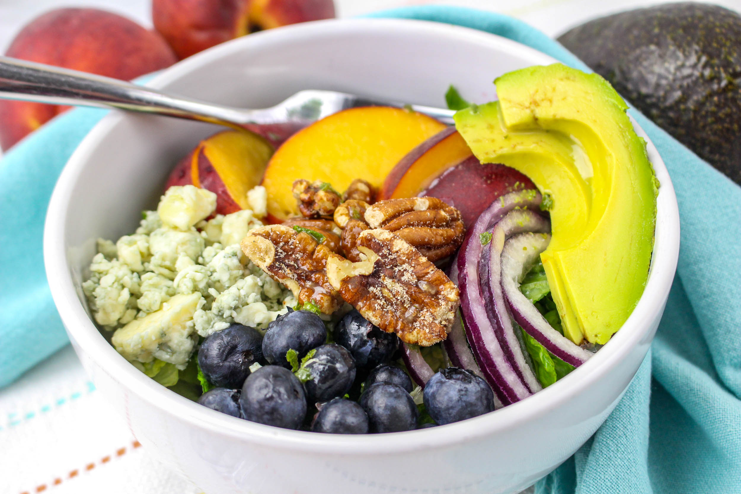 Peach salad ingredients in a bowl with fork.