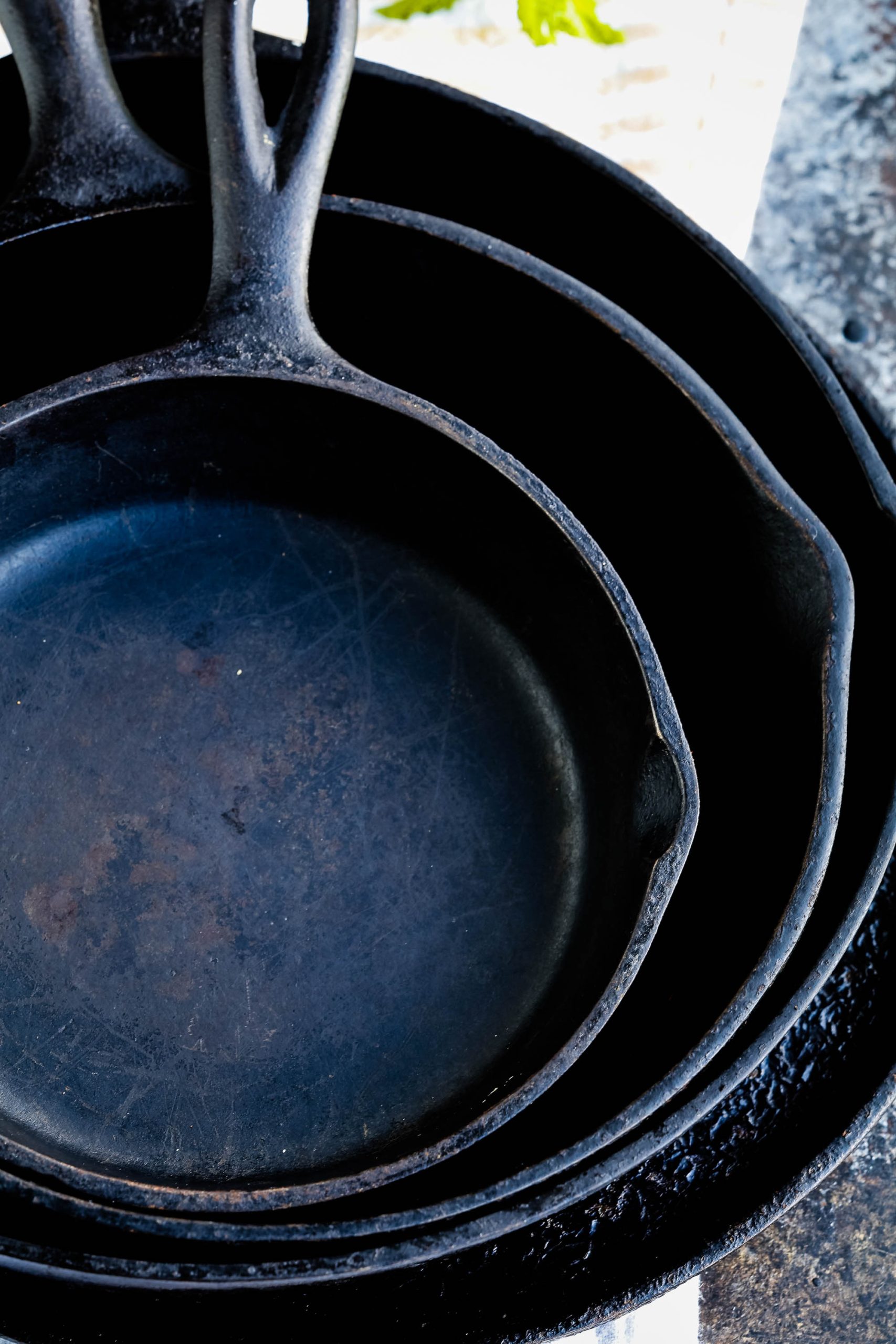 Flatlay of four seasoned cast iron skillets.