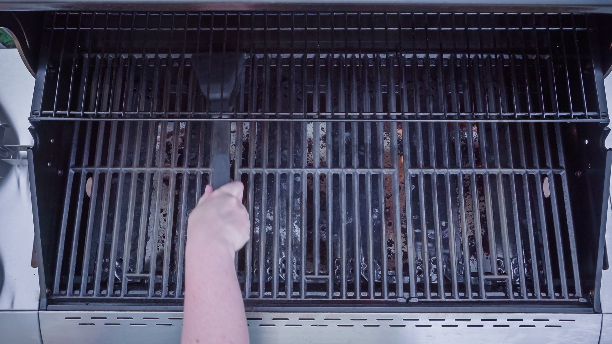 Cleaning gas grill with a wire brush.