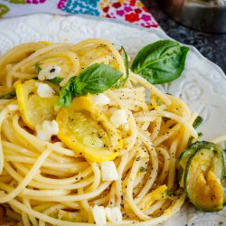 A twist of spaghetti noodles on a plate with squash.