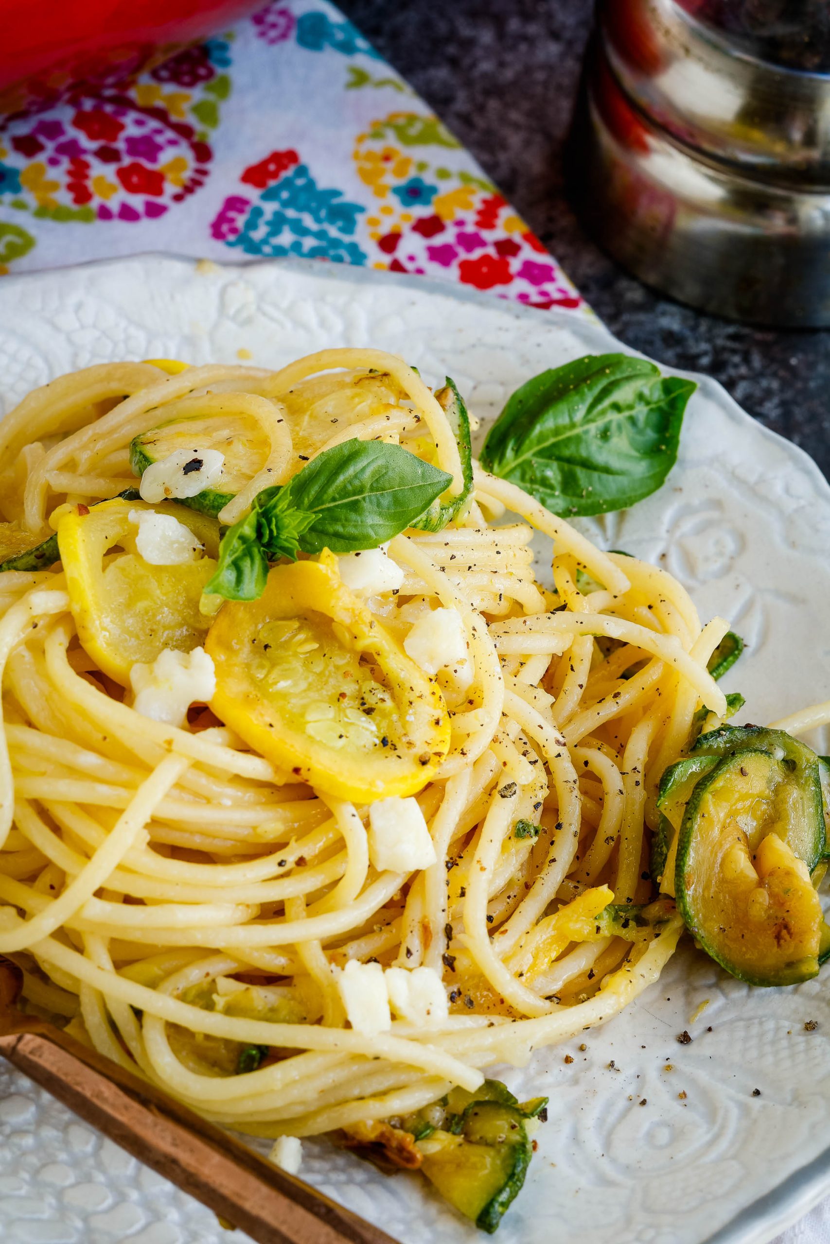 A twist of spaghetti noodles on a plate with squash.