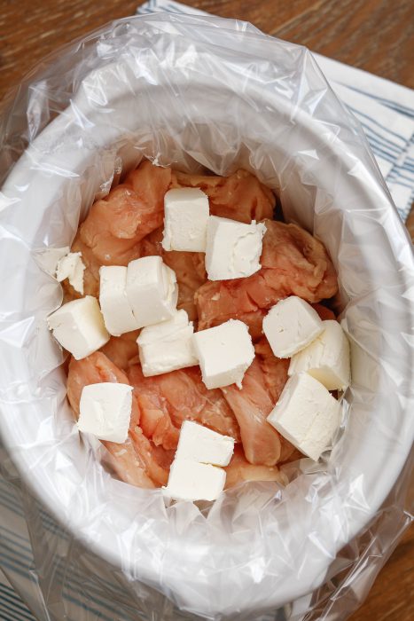 Chicken and cream cheese in a slow cooker.