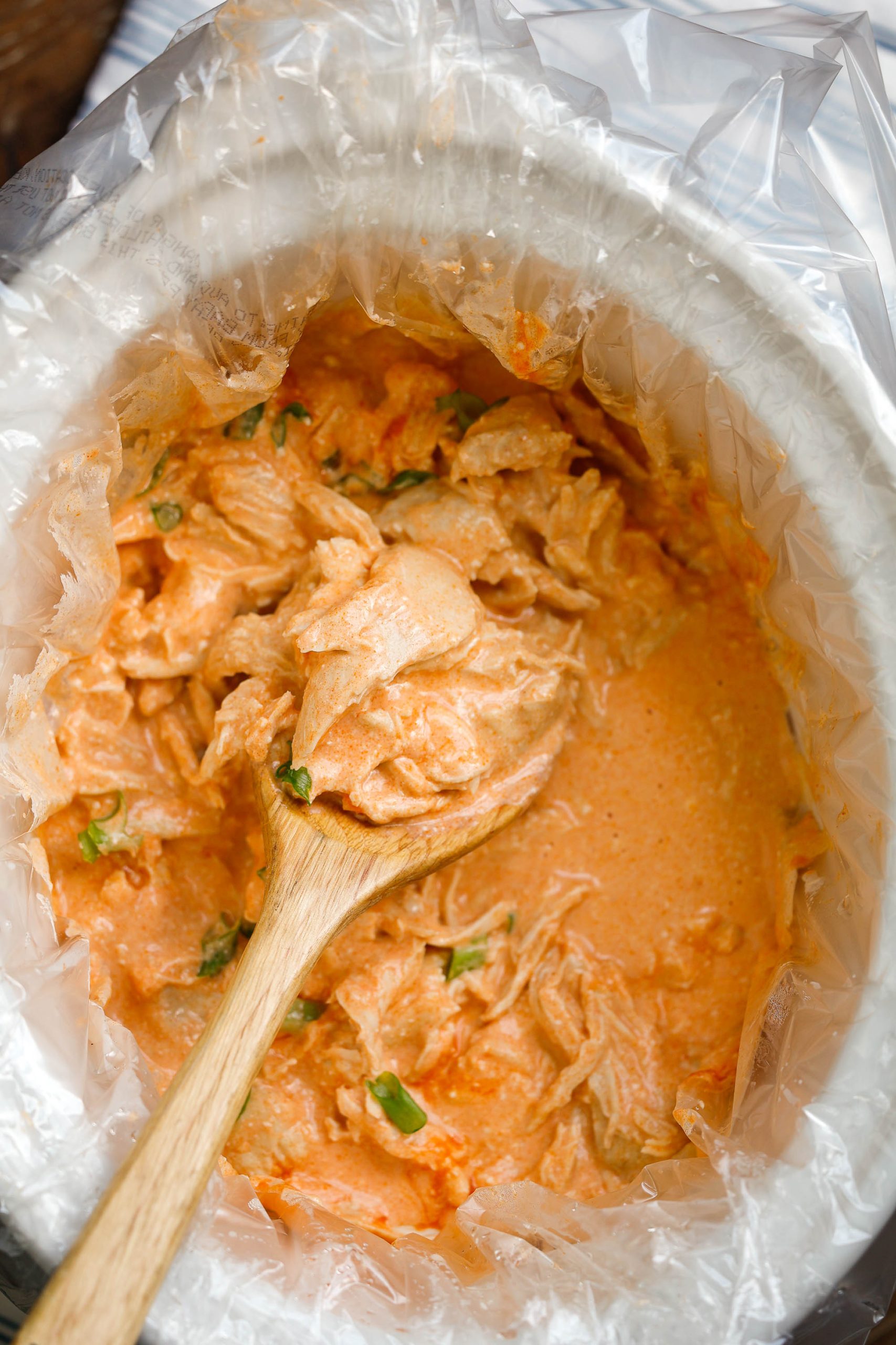 Shredded chicken in buffalo sauce served with a spoon.