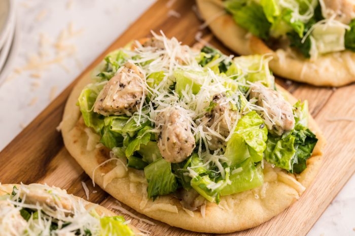 Small flatbread topped with salad and chicken.