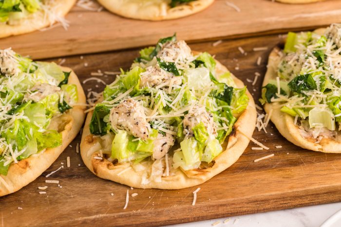 Three small flatbread topped with salad and chicken.