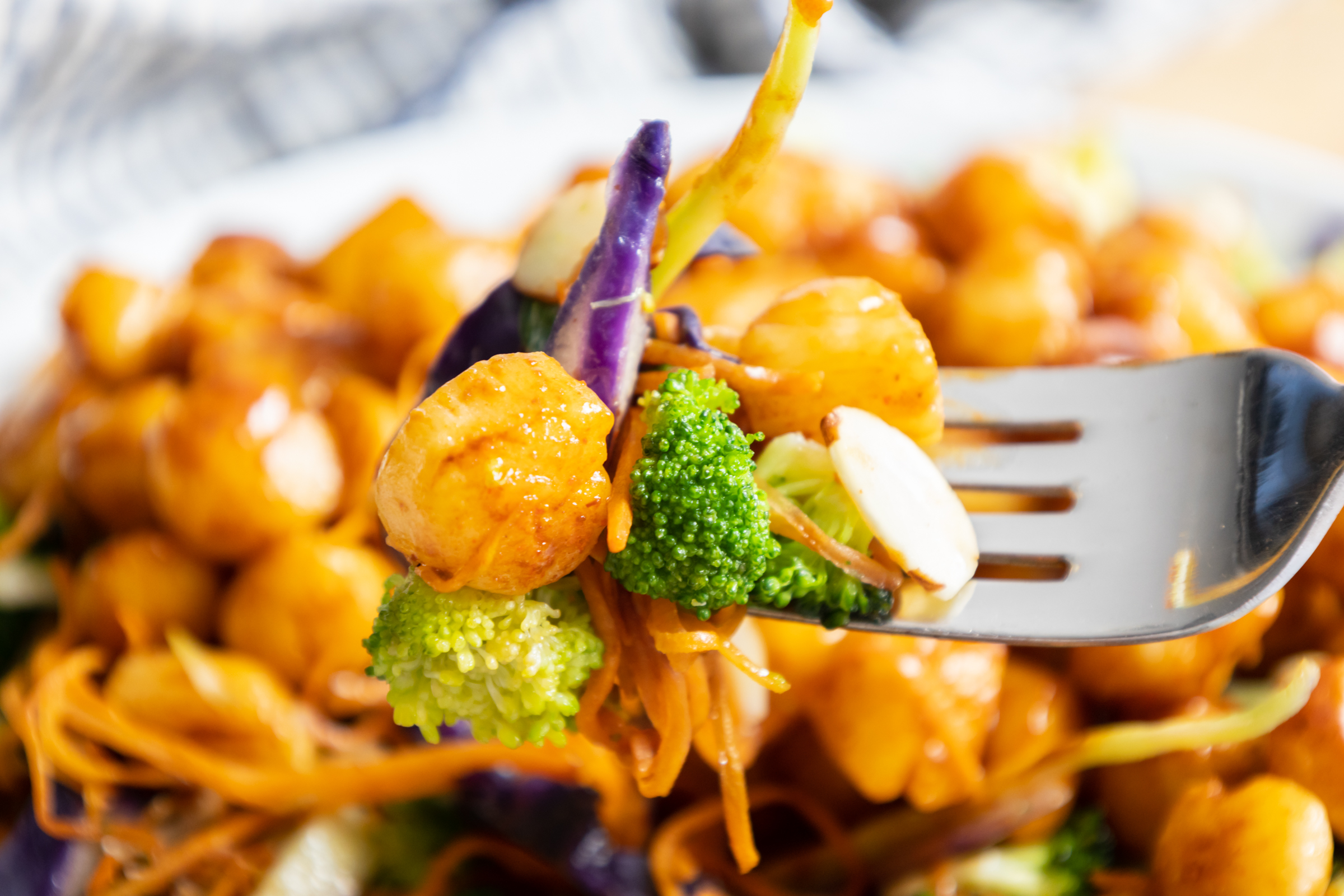 Bite of Bay scallops and broccoli slaw on a fork.