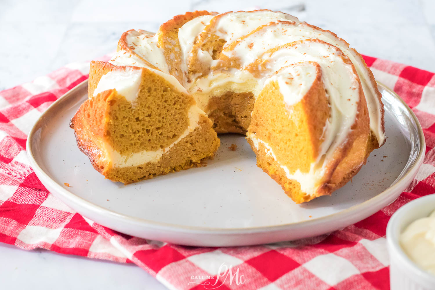 Wedge cut out of a pumpkin bundt cake with cream cheese ribbon in it.