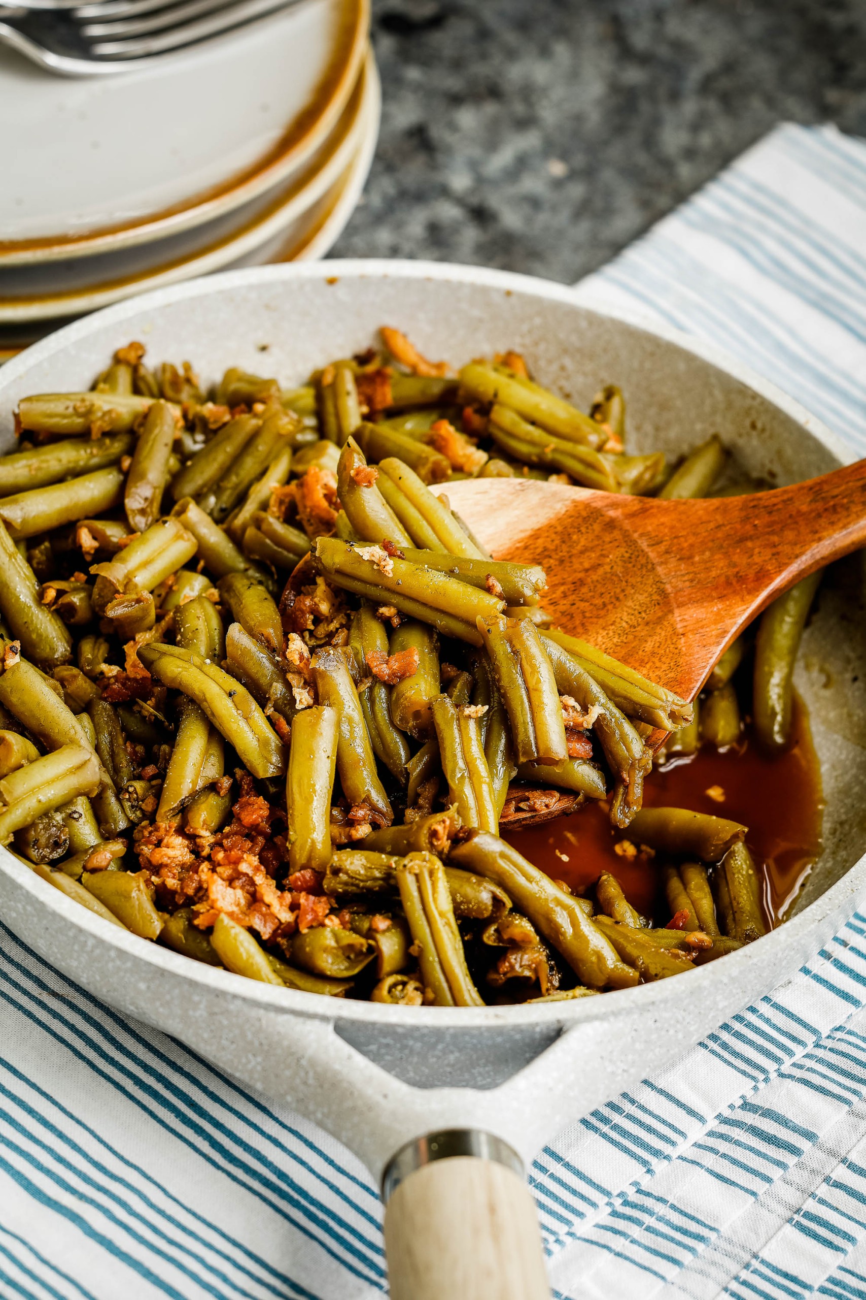 Green vegetable in a skillet with serving spoon.