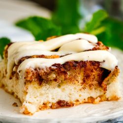 A piece of cinnamon roll cake on a plate.