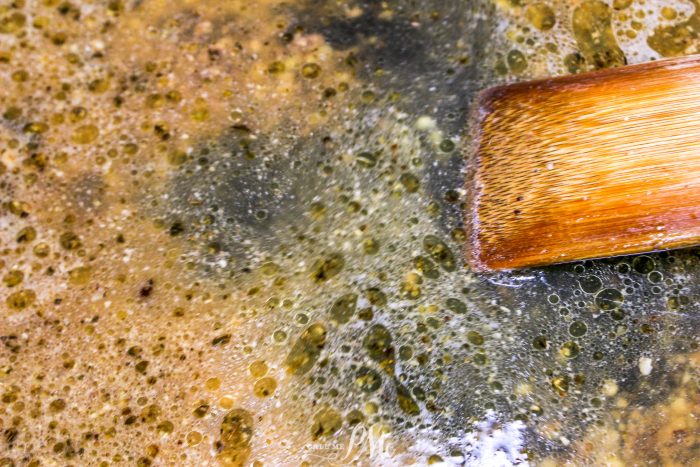 A wooden brush is in a bowl of soapy water.