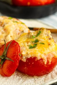 Stuffed tomatoes with cheese and herbs on a plate.