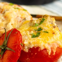 Stuffed tomatoes with cheese and herbs on a plate.