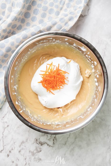 A bowl with whipped cream and carrots in it.