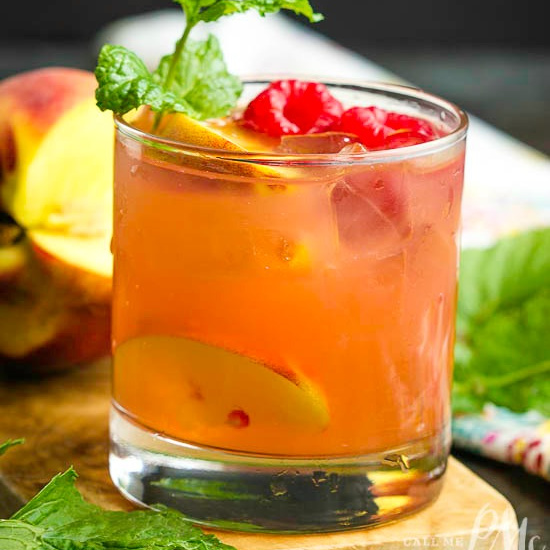 A cocktail with raspberries and peaches.
