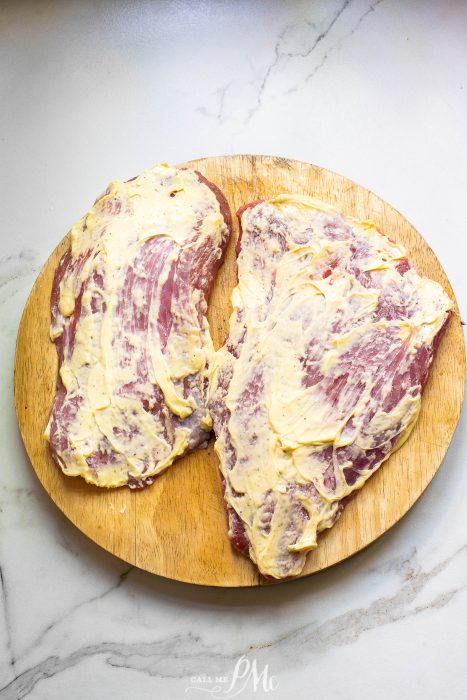 Two pieces of meat on a wooden cutting board.