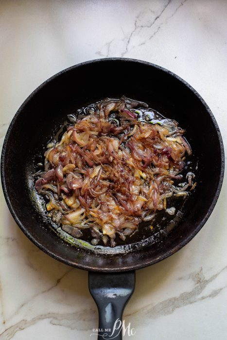 Fried onions in a frying pan on a marble counter.