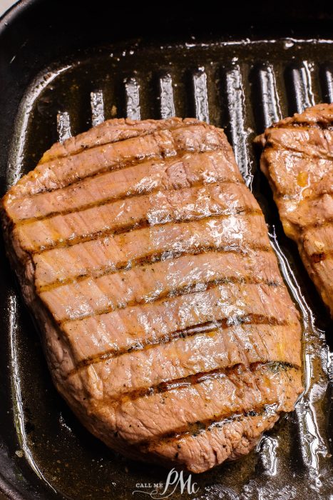 Two steaks are being cooked in a frying pan.