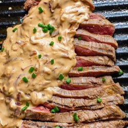 A steak on a grill with a sauce on it.