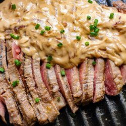 A steak on a grill with a sauce on it.