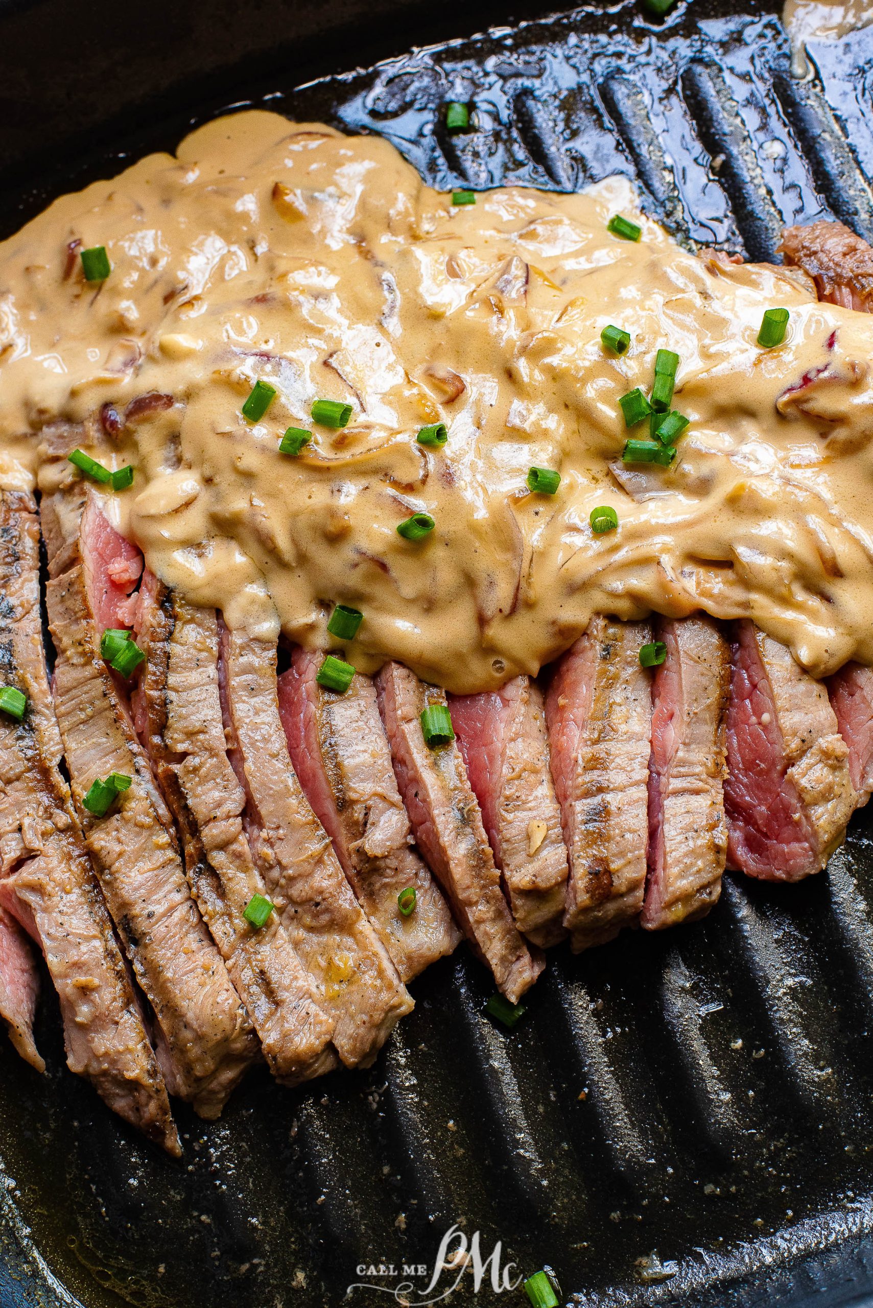 A steak on a grill with a sauce on it.