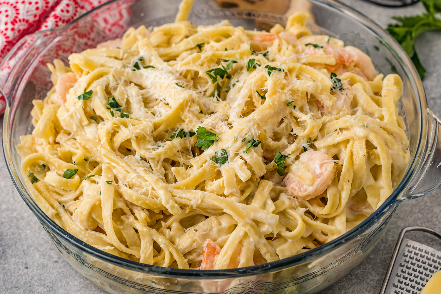 Shrimp and fettuccine pasta in a large glass bowl.