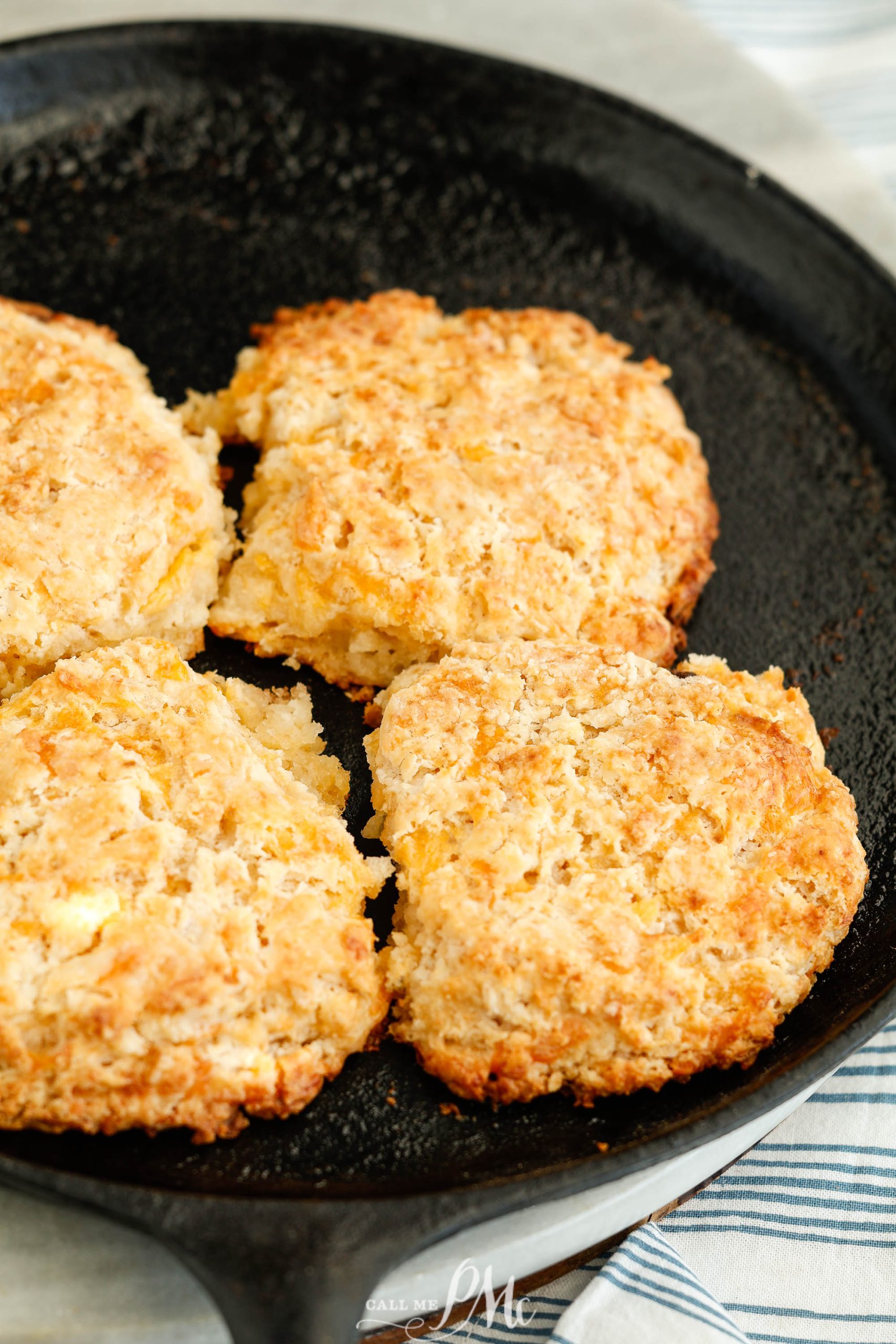 A cast iron skillet with four biscuits in it.
