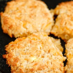 Four biscuits in a skillet on a table.