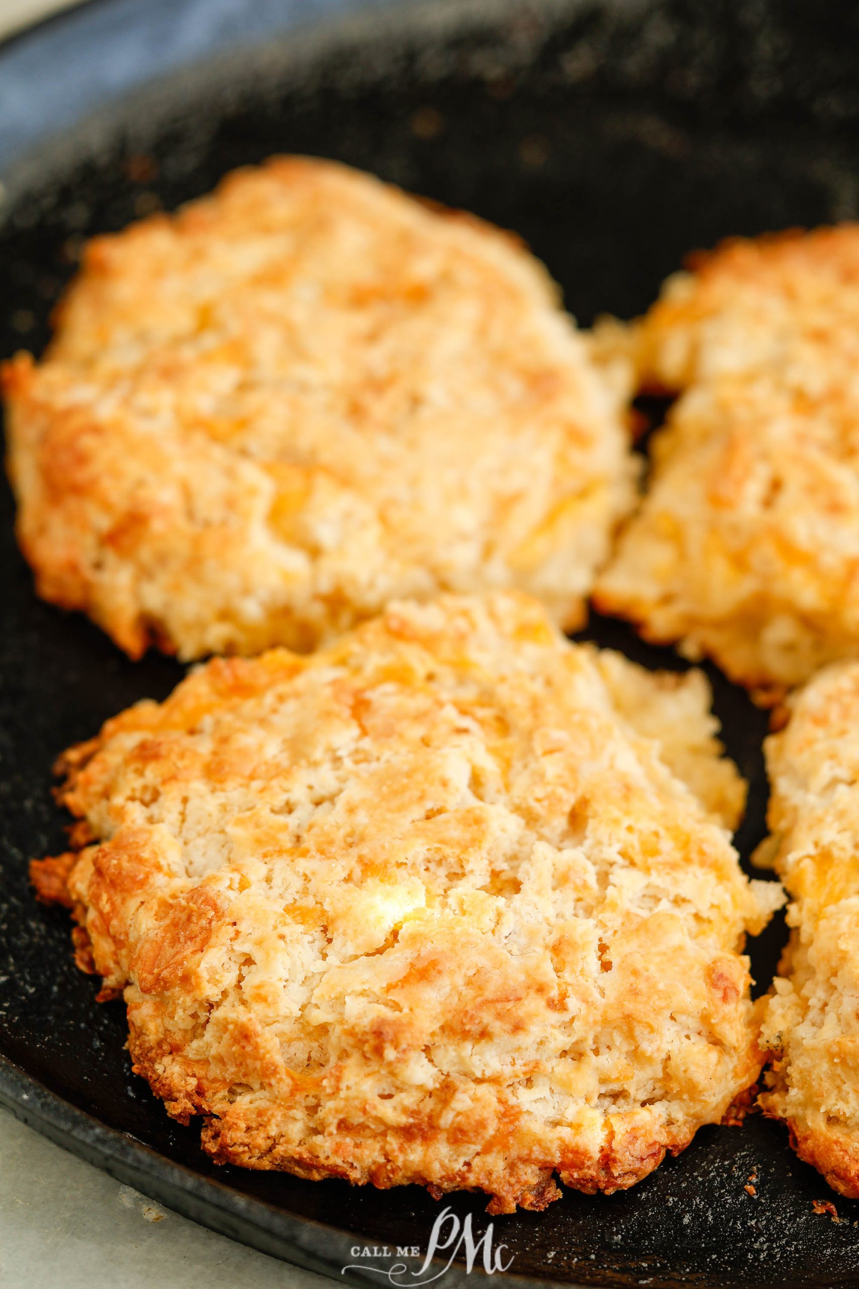 Four biscuits in a skillet on a table.