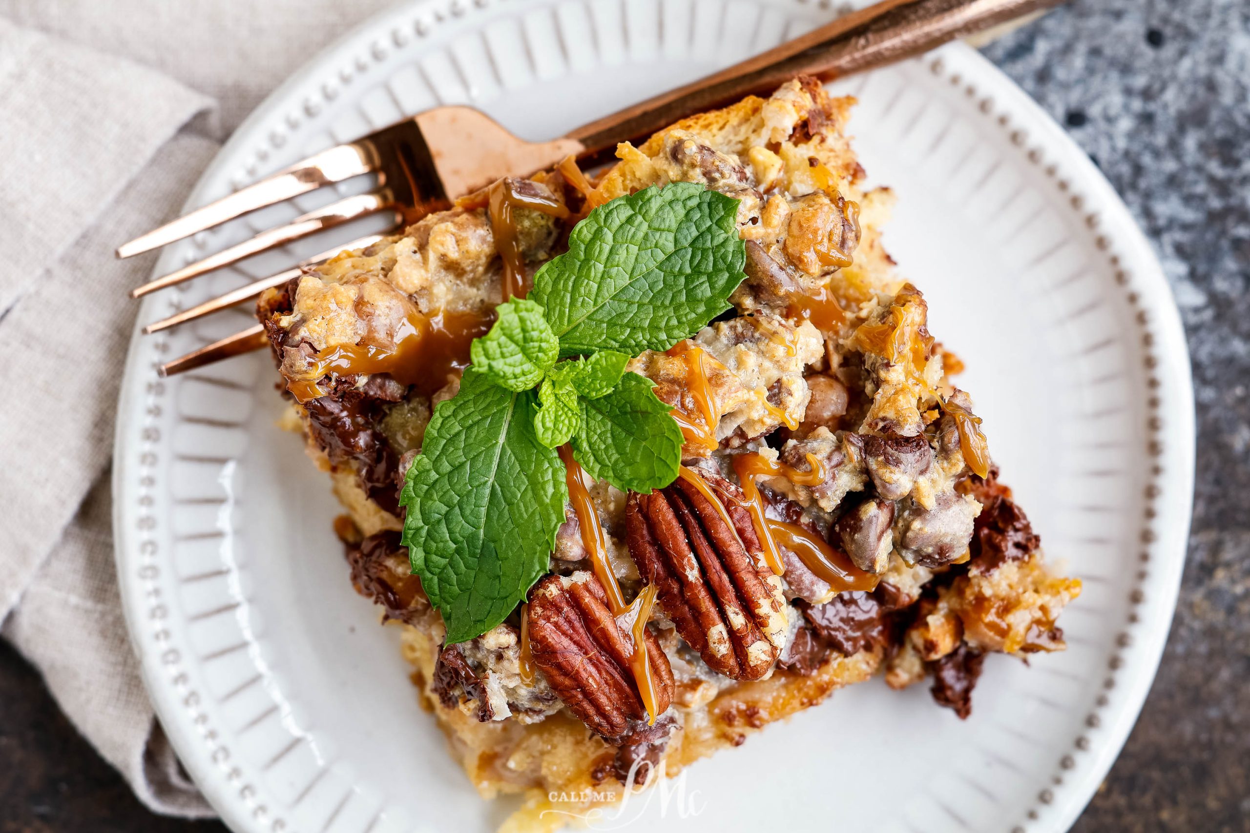 Flat lay of bread pudding topped with pecans and mint for garnish.