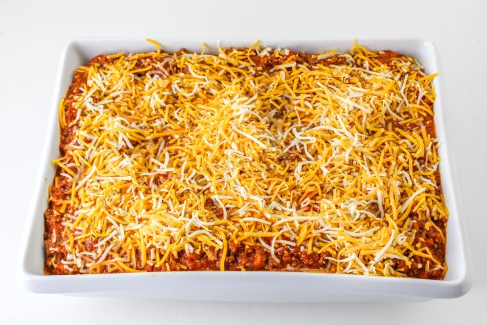 A casserole dish topped with cheese and sour cream.