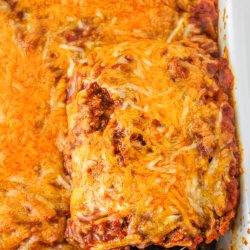 Lasagna in a baking dish with a spatula.