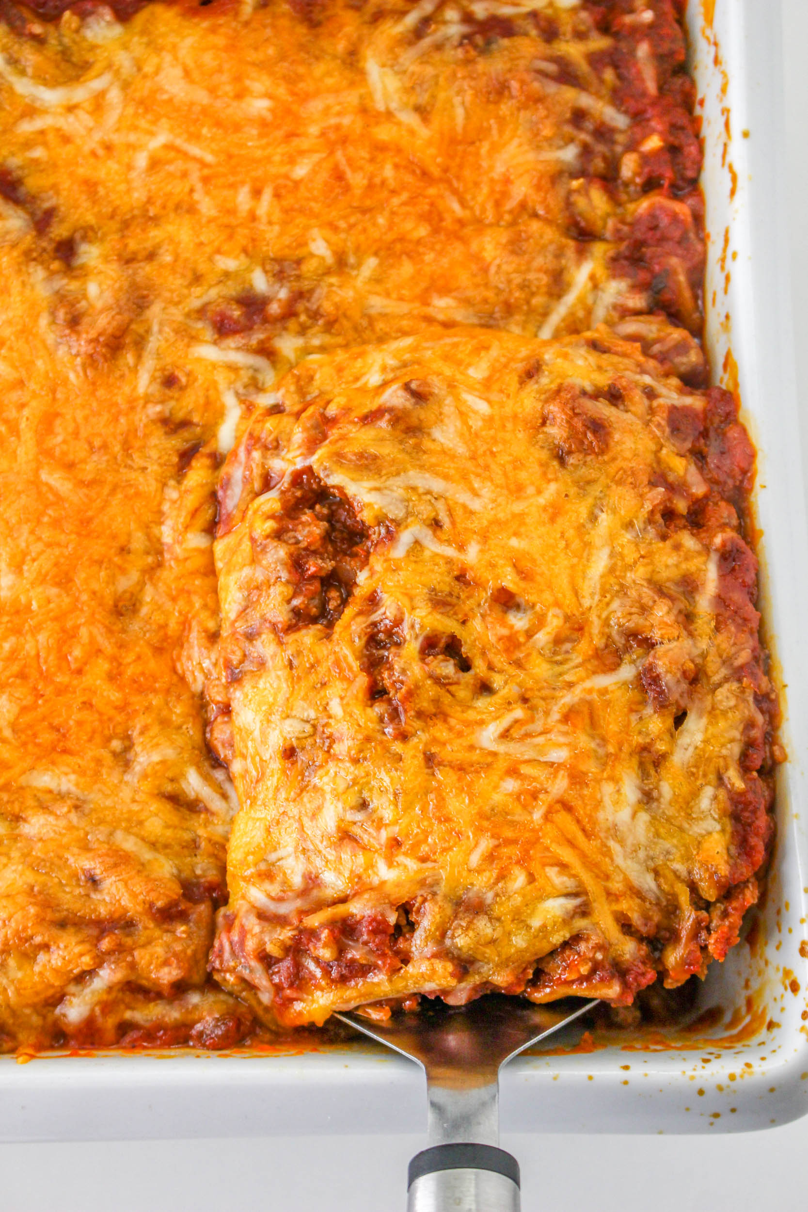 Lasagna in a baking dish with a spatula.