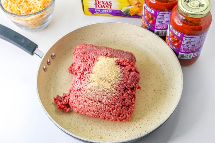 Meatloaf in a frying pan next to a bottle of ketchup.