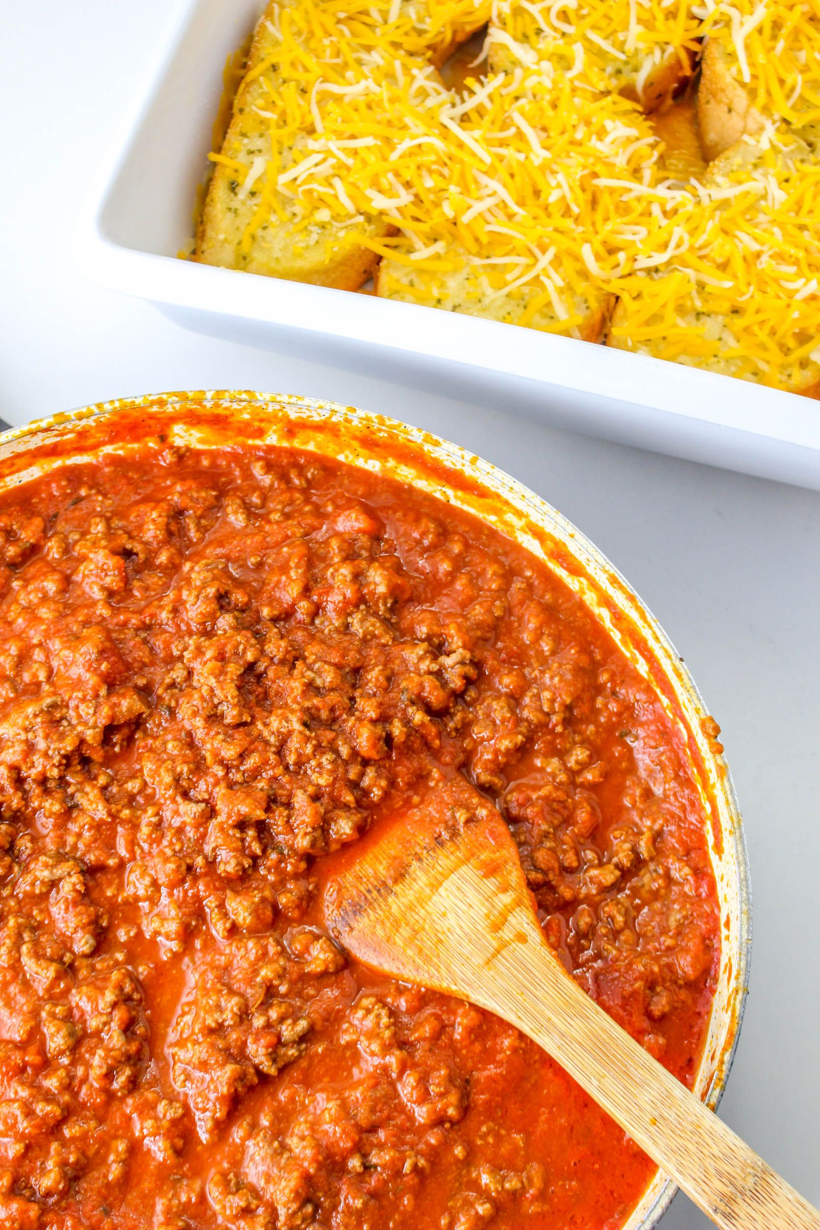 A bowl of chili with a wooden spoon next to it.