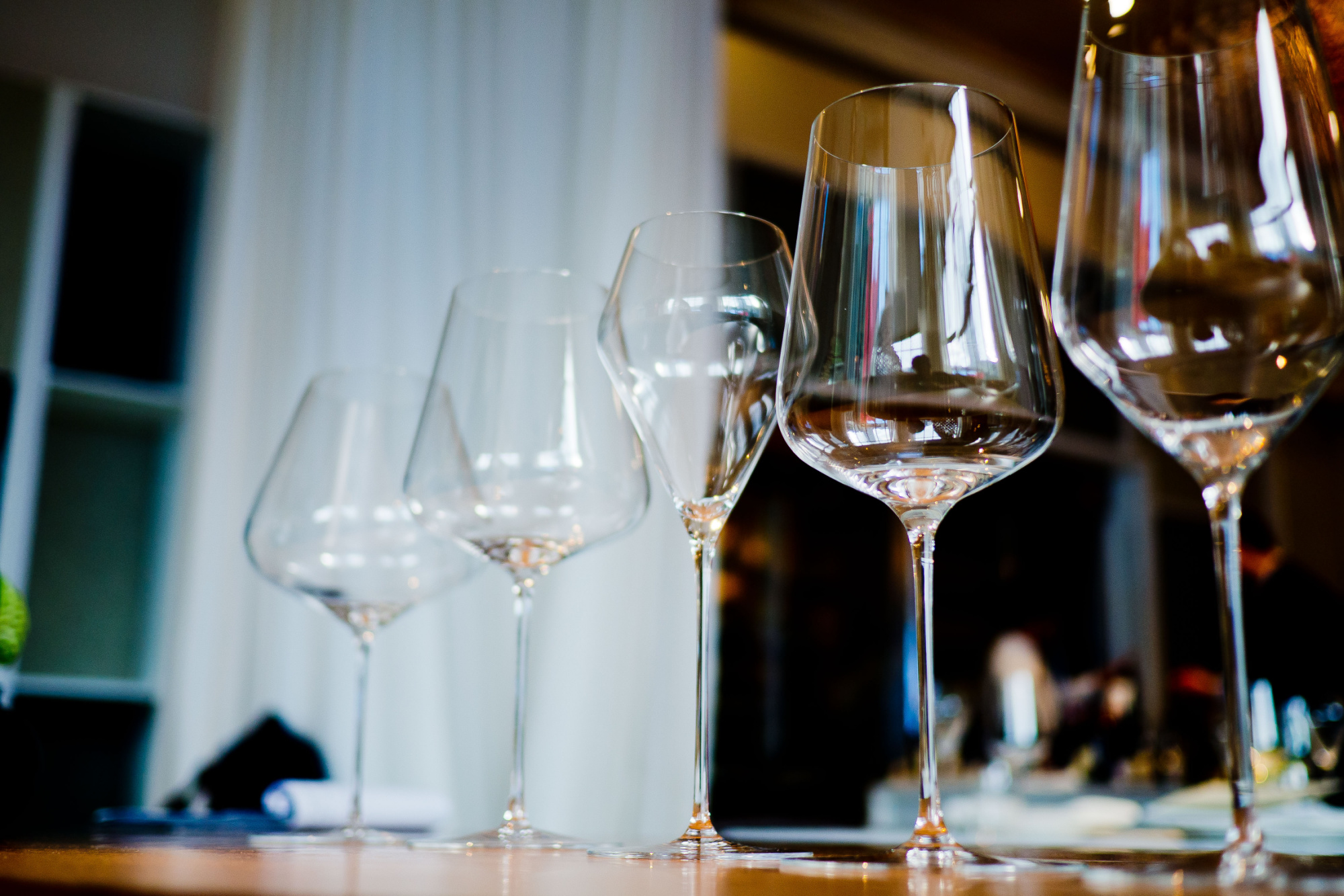 A row of wine glasses lined up on a table.